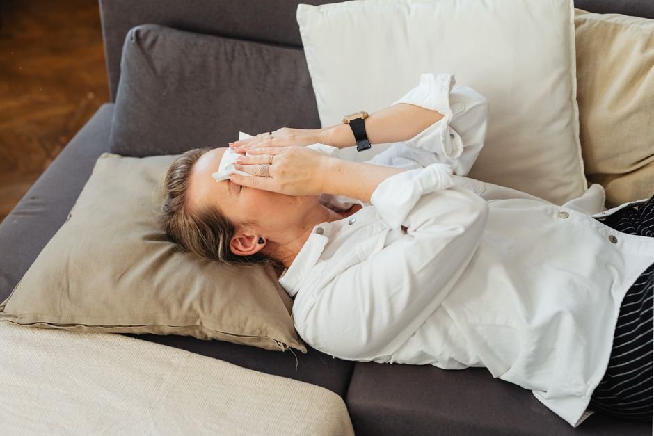 An adult resting quietly on a couch in a dim, low-stimulation living room