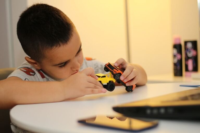 A child sitting on the floor, engaged in play with toy cars lined up in a row.