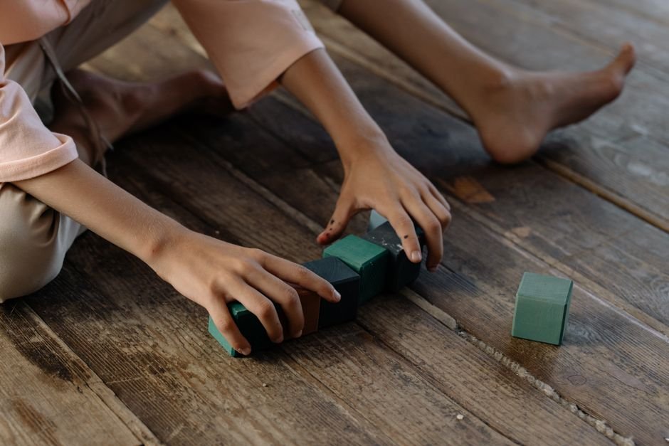 A child playing with a set of textured building blocks on the floor