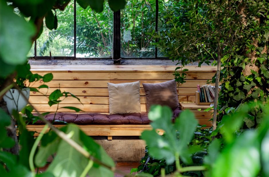A small home corner with soft cushions, a blanket, and a low shelf of quiet toys, set apart from the main living space