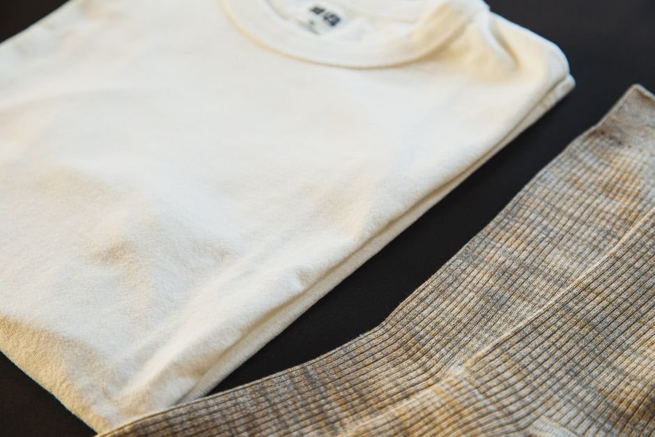 Folded soft cotton clothing without visible tags laid out on a bed