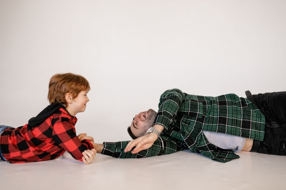 A parent crouching at eye level beside a child on a park bench, the two of them talking calmly.