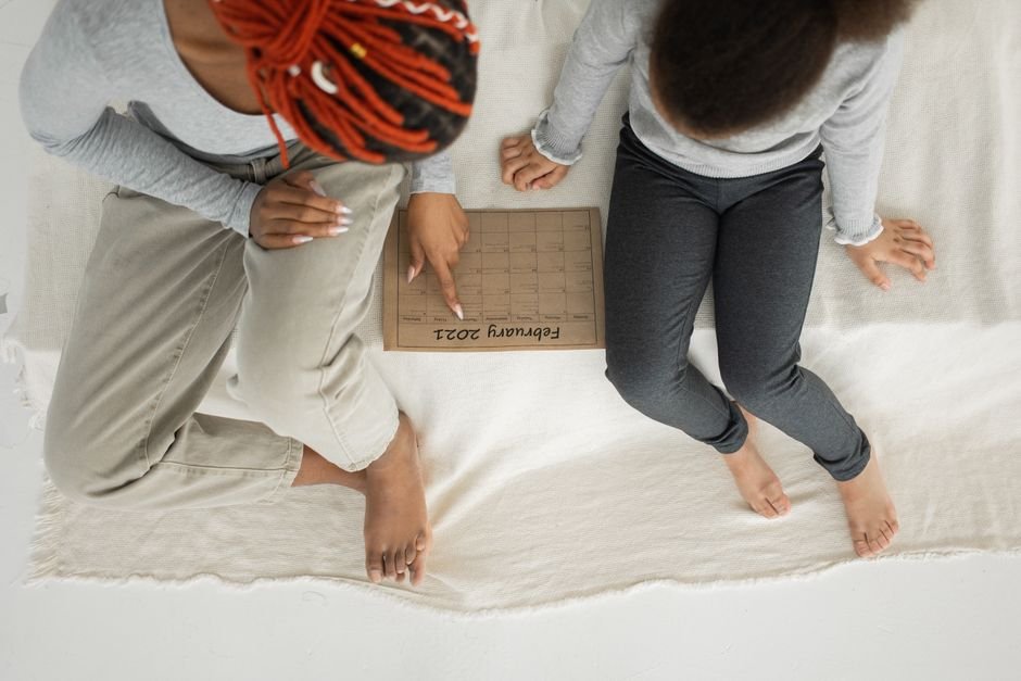 A parent and child looking together at a calendar on the wall
