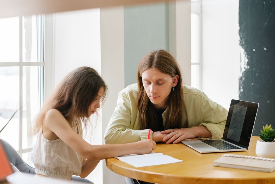 A parent and teacher sitting together reviewing paperwork at a school table