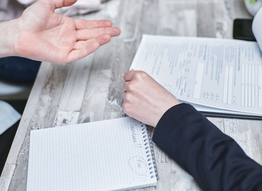 A parent reviewing handwritten notes at a table before a school meeting