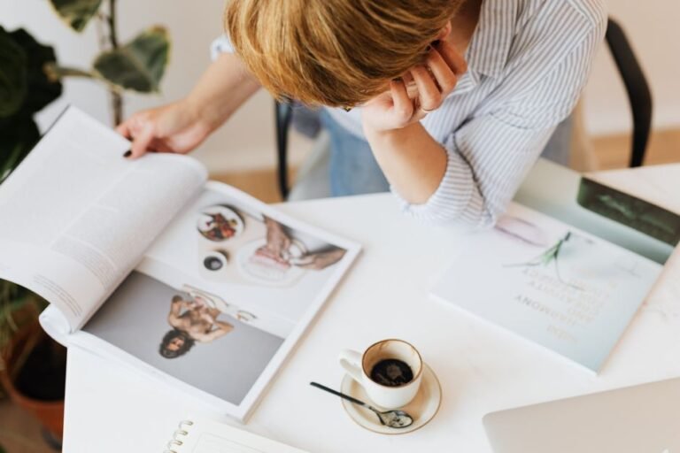 A person sitting at a desk deeply focused on a hobby project surrounded by related books and materials