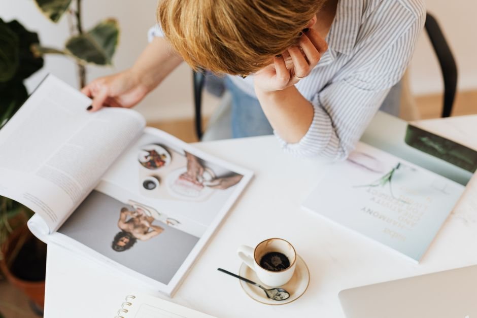 A person sitting at a desk deeply focused on a hobby project surrounded by related books and materials
