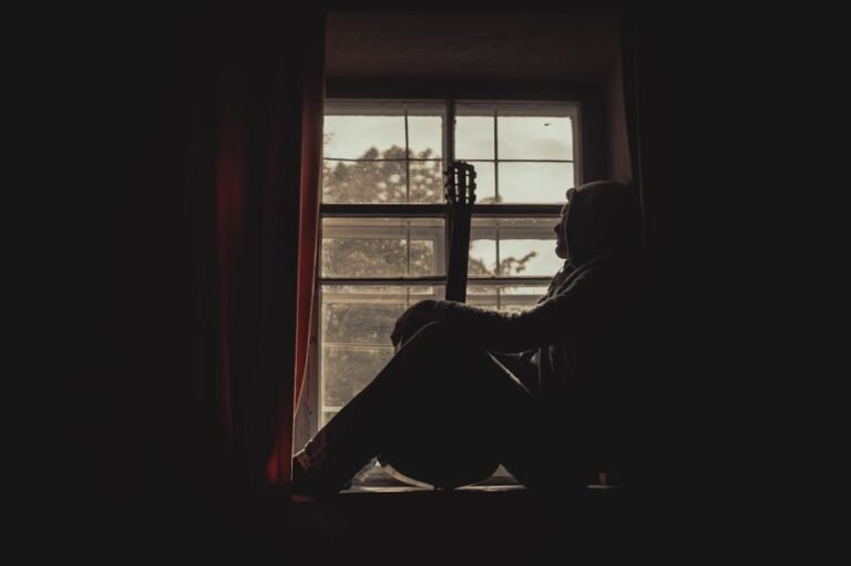 A person sitting quietly by a window, looking thoughtful