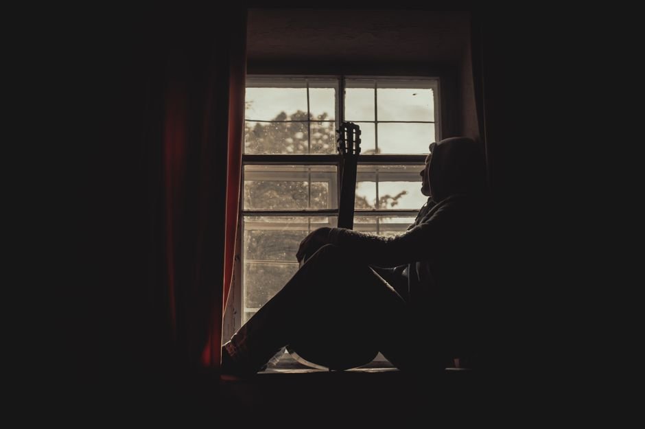 A person sitting quietly by a window, looking thoughtful