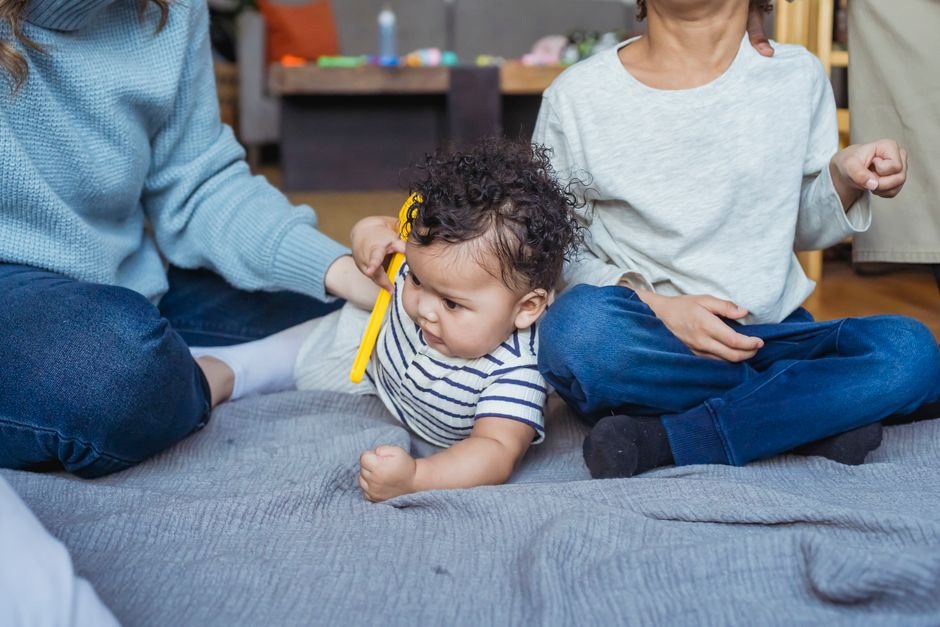 Two siblings sitting on the floor together, playing with toys