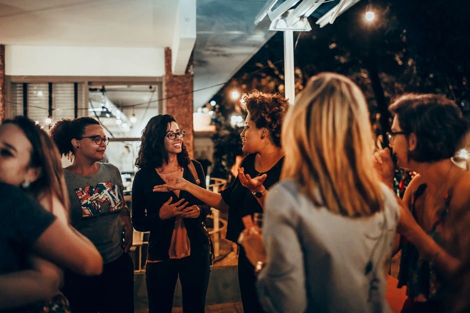 A small group of adults talking and smiling together at a community event.