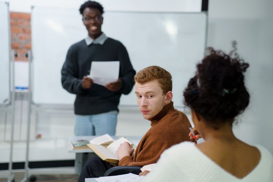 A teenager raising a hand and speaking during a classroom discussion.
