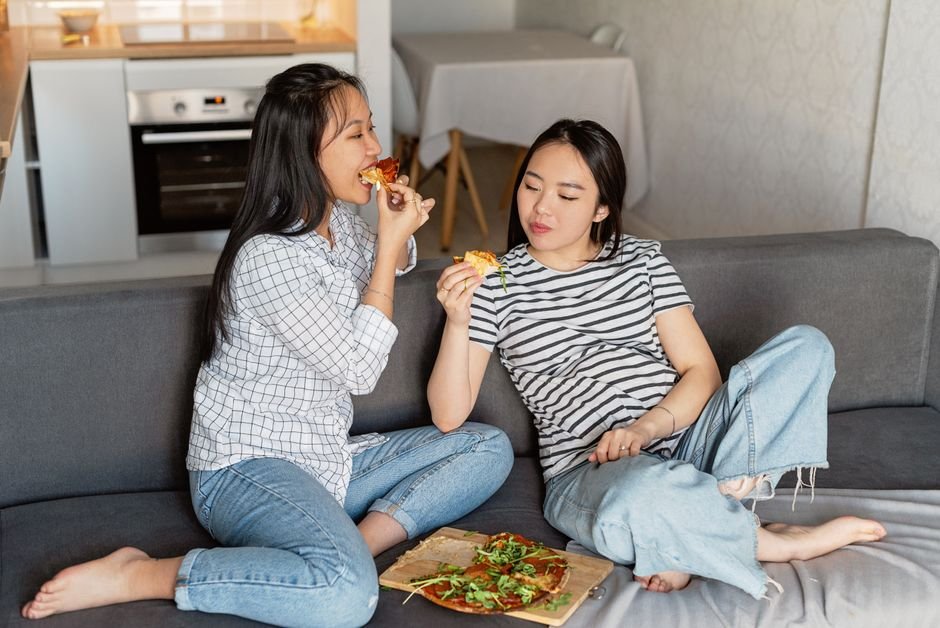 Two friends sitting together comfortably, each quietly absorbed in their own activity
